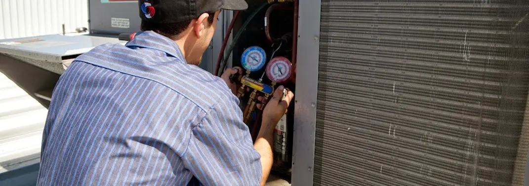 HVAC technician servicing a condenser unit in Crystal